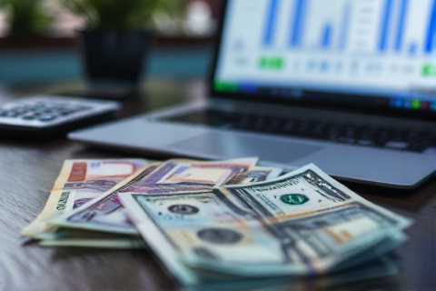 Bangladeshi Taka and US dollar bills on desk with calculator showing exchange rates